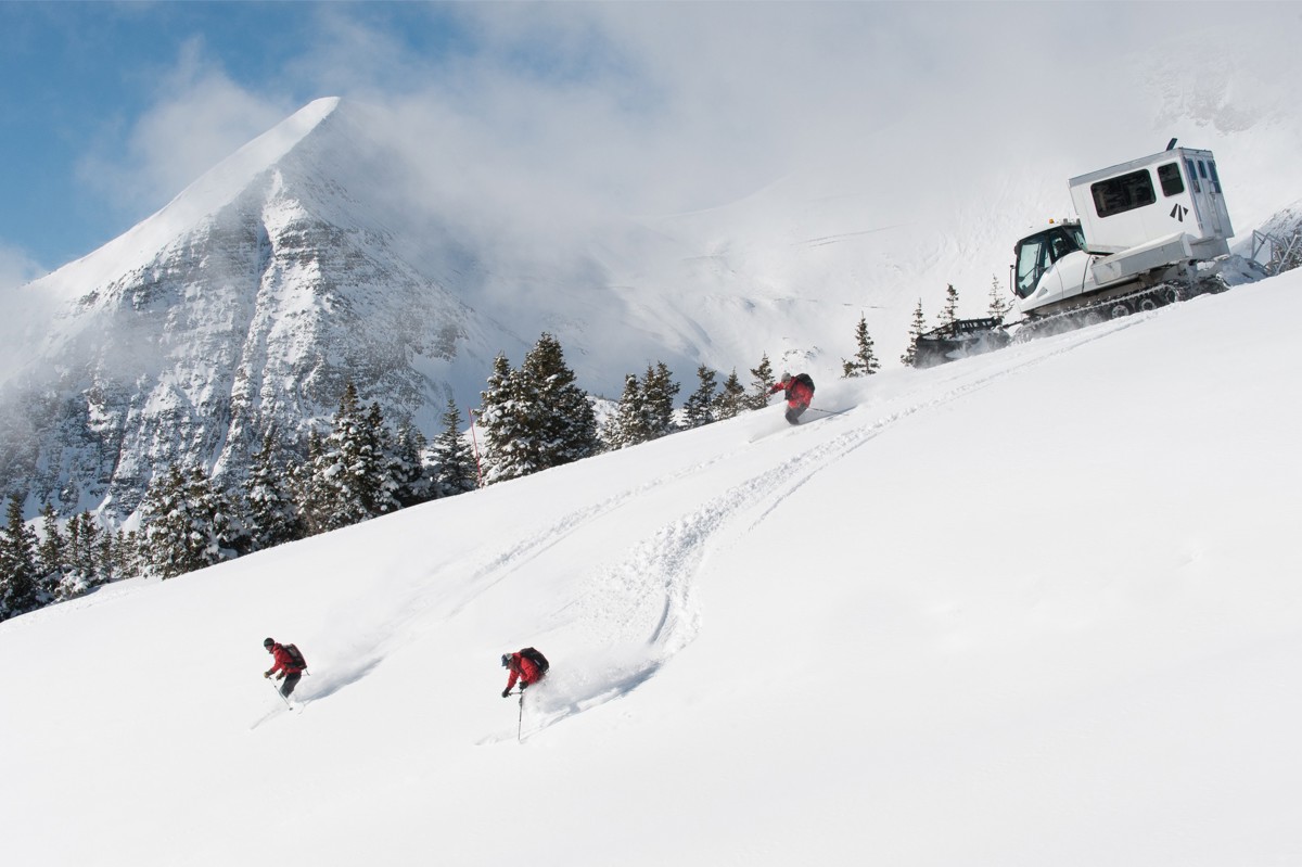 Skiers disembarking down a mountain from a catski,